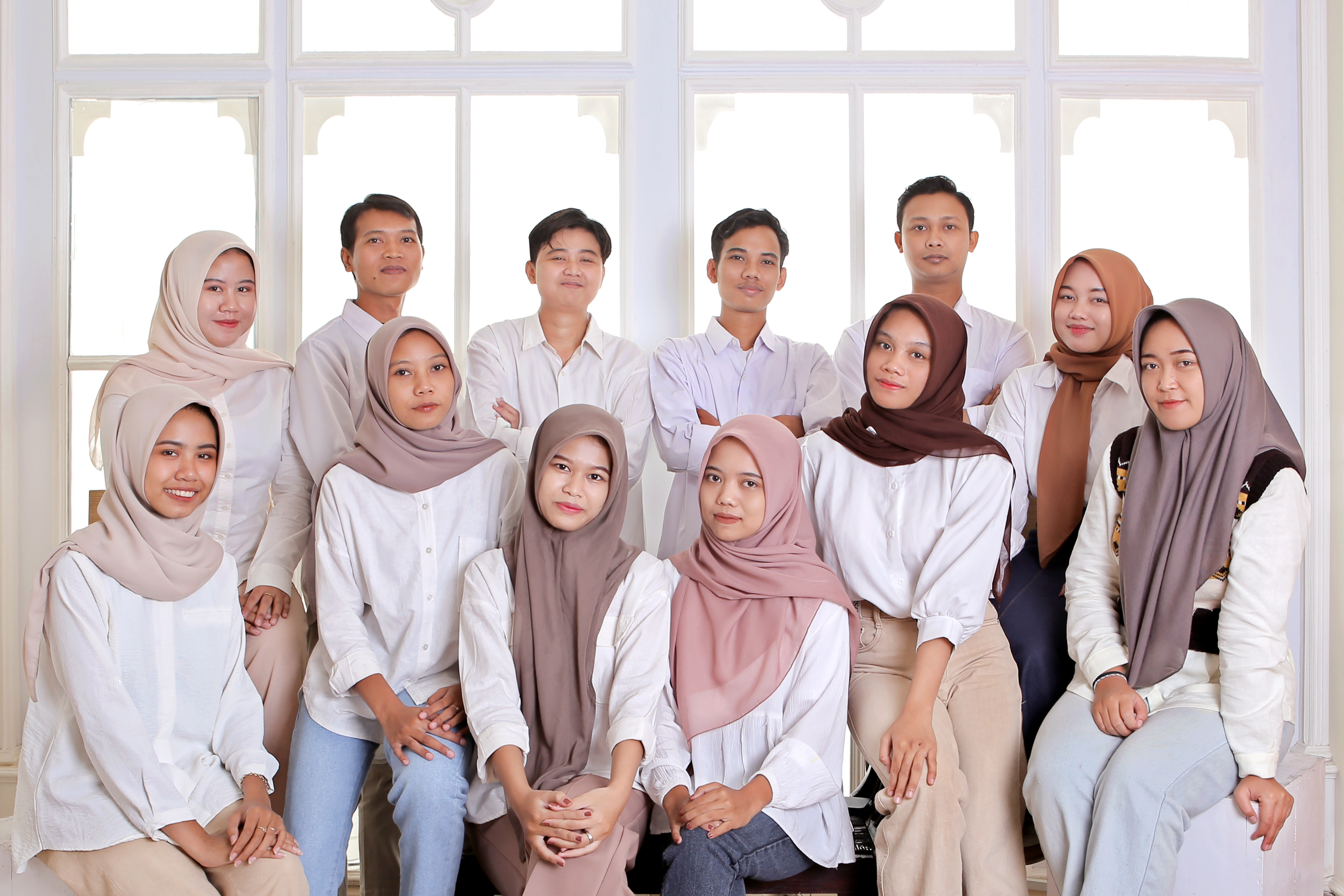 Corporate team of 12 people posed professionally in business attire against modern office backdrop