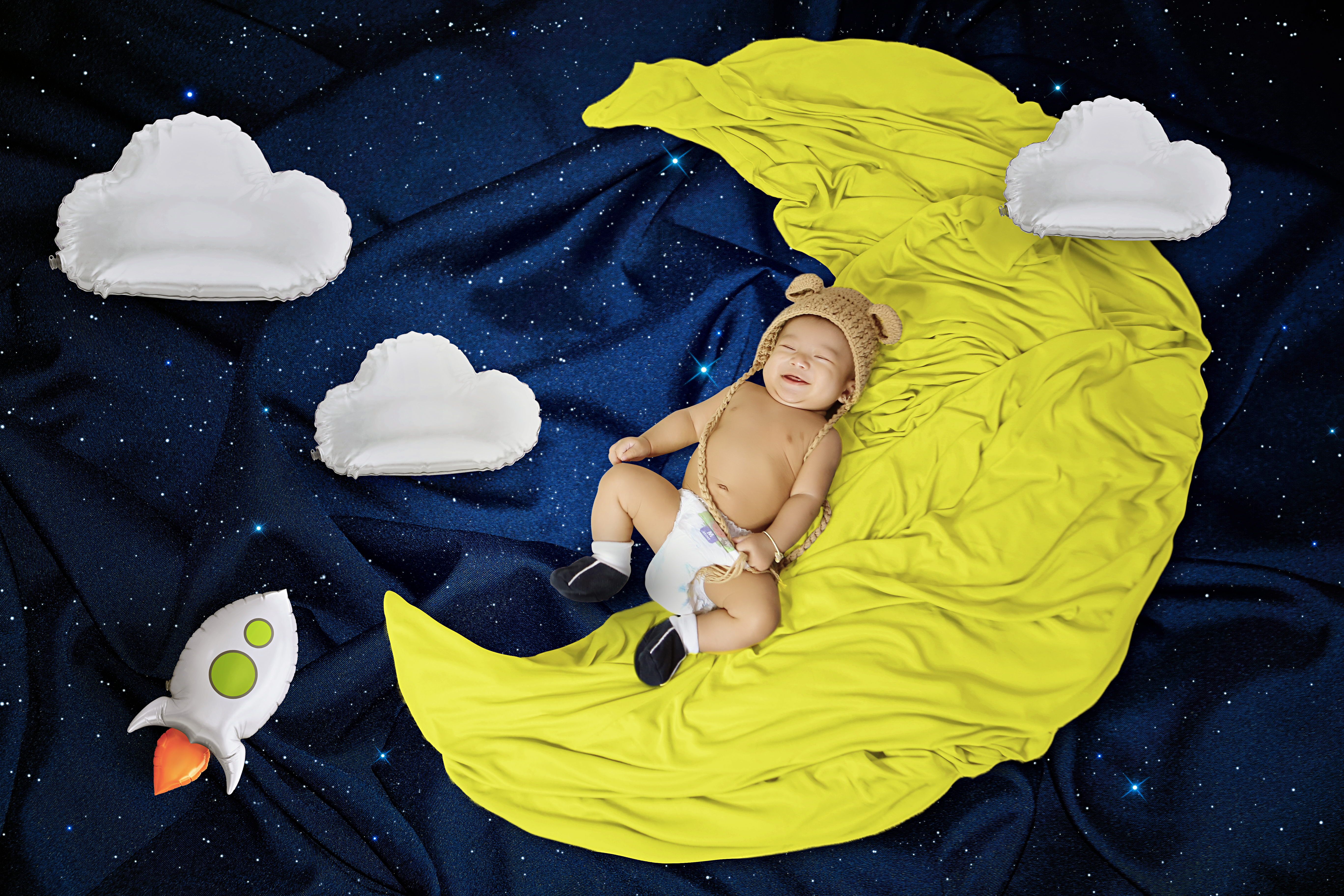 Adorable baby laughing while sitting among colorful toys in soft natural light