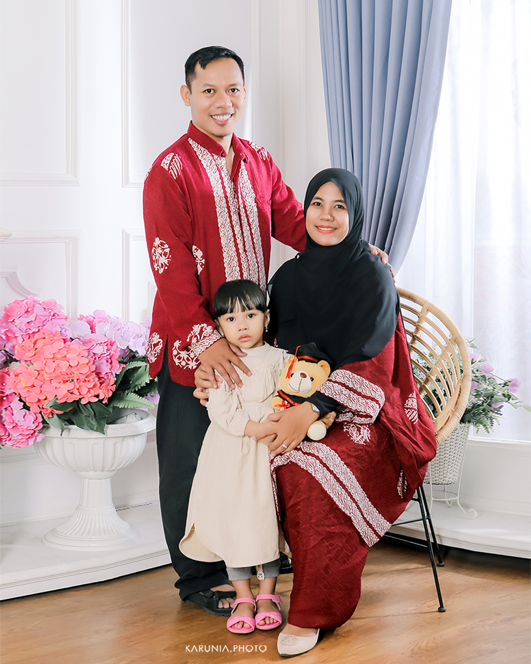 Three siblings sitting on wooden steps in coordinating outfits with genuine smiles and relaxed poses