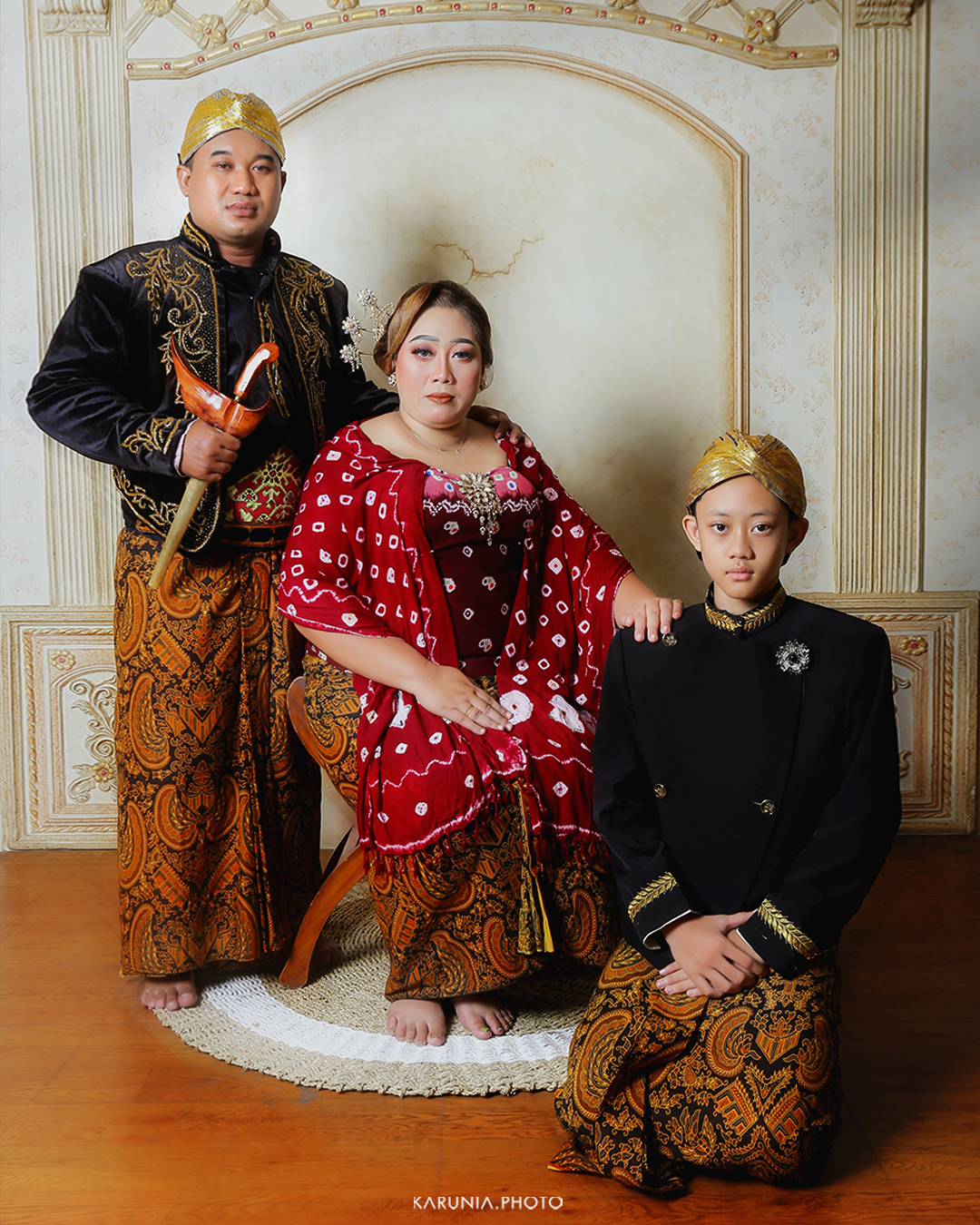 Three siblings sitting on wooden steps in coordinating outfits with genuine smiles and relaxed poses