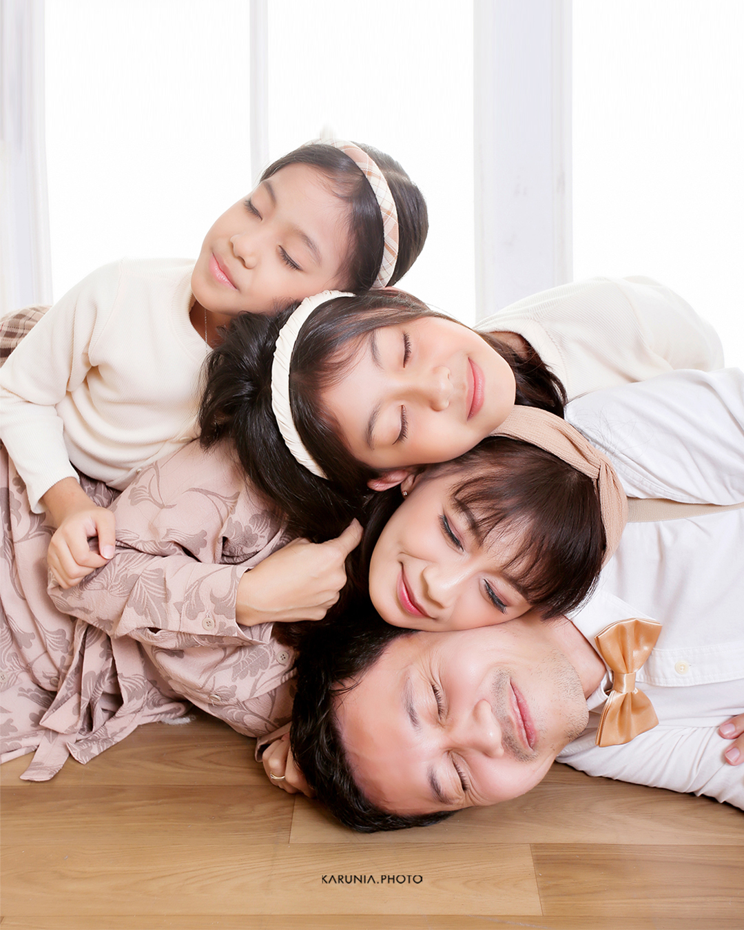 Family laughing together while jumping on a beach at sunset with golden light illuminating their joy