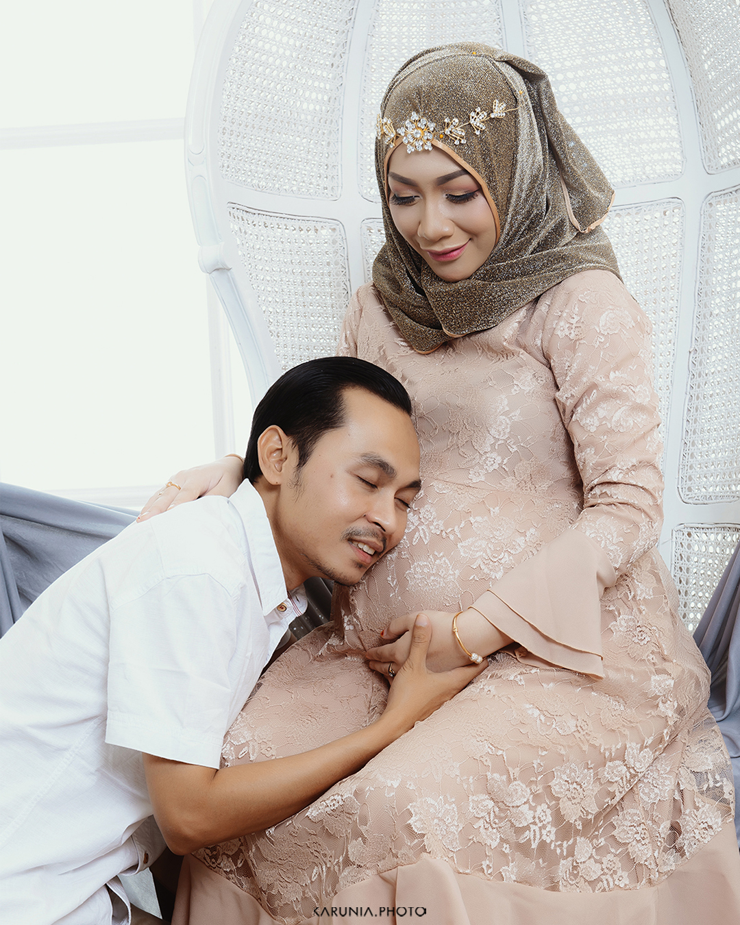 Silhouette of pregnant woman standing by ocean shore at sunset with glowing rim light