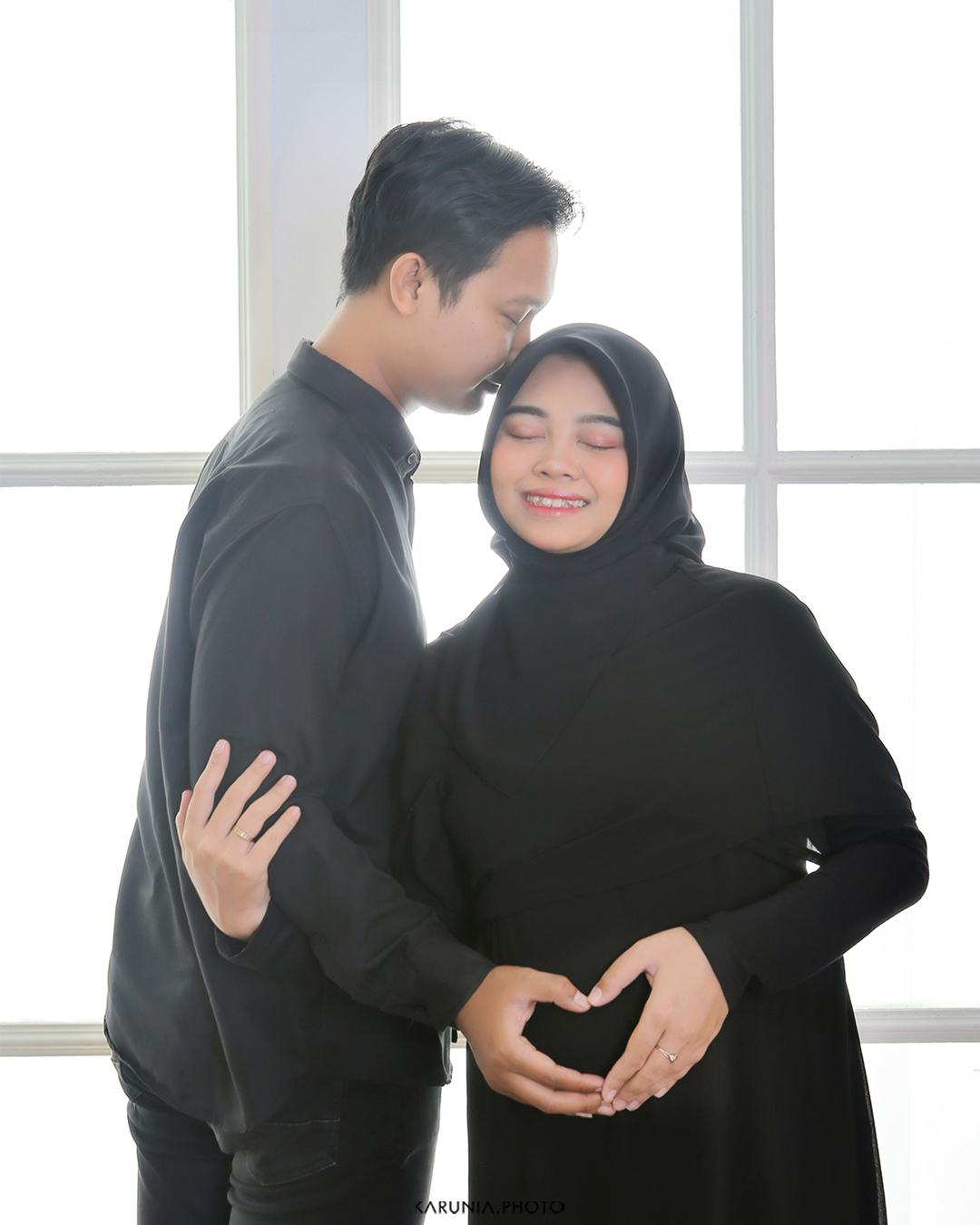 Playful maternity portrait with mother holding ultrasound photo above her belly
