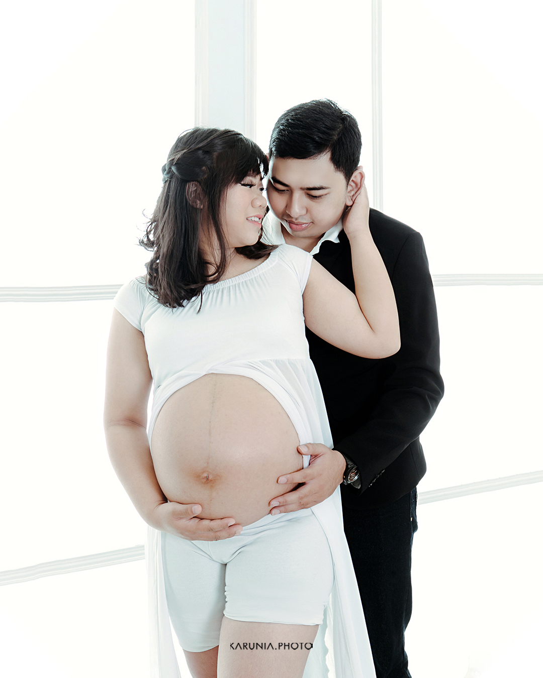 Silhouette of pregnant woman standing by ocean shore at sunset with glowing rim light