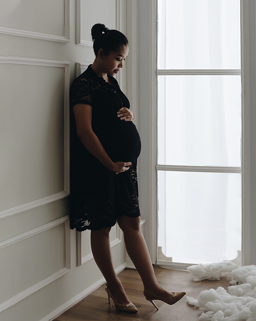 Silhouette of pregnant woman standing by ocean shore at sunset with glowing rim light