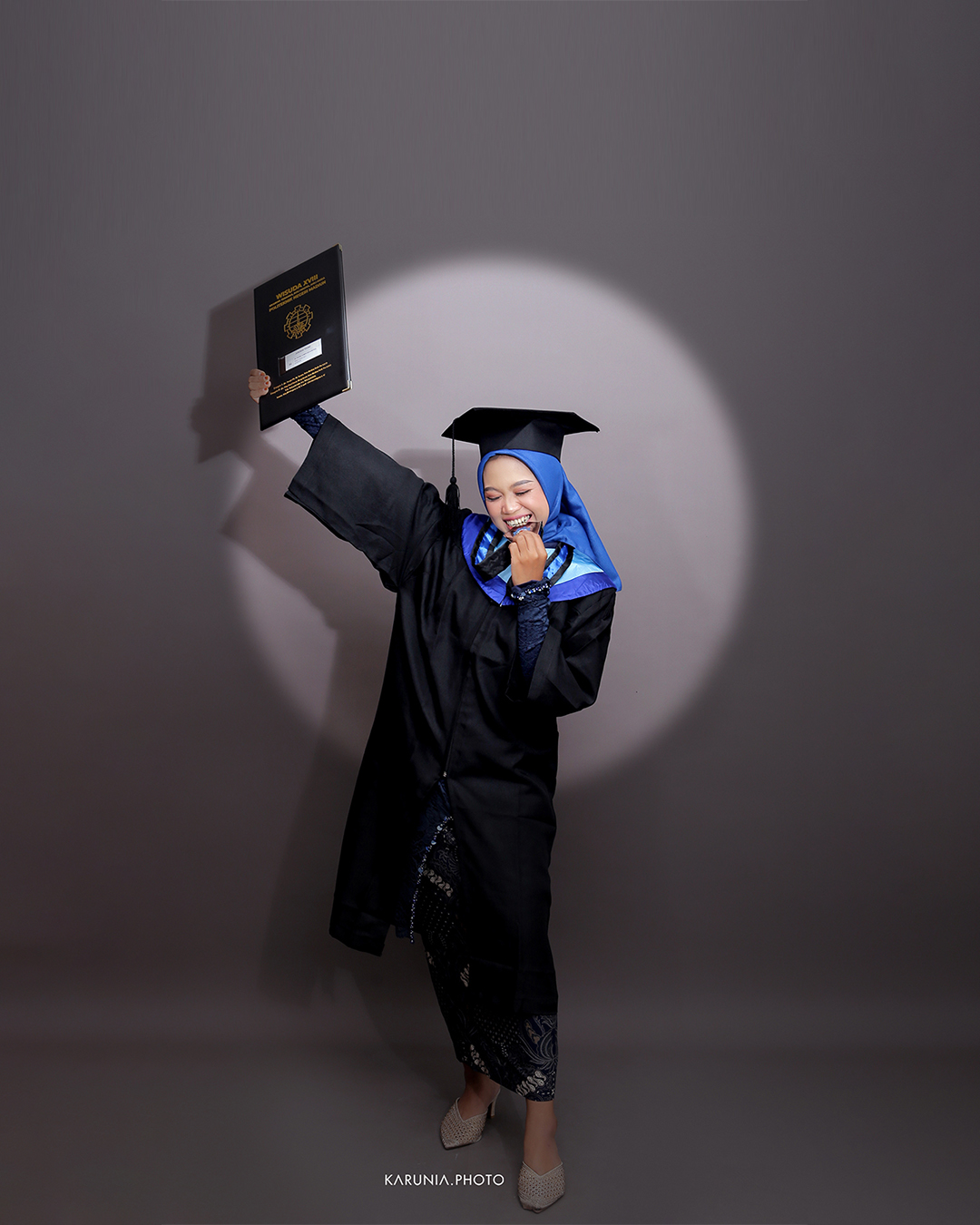 Group of friends in caps and gowns cheering together with arms around each other